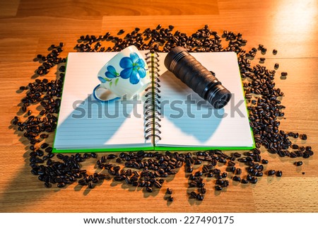 camera and coffee cup on book  coffee beans  wooden background