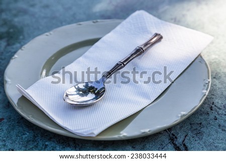 spoon on white empty plate on table waiting for food serving.
