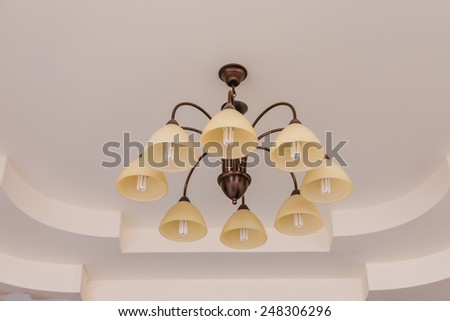 Yellow lamps with brass structure on ceiling in ballroom