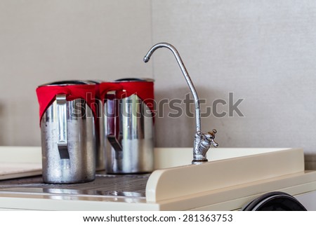Modern curved mixer tap and stainless steel jug of cold water