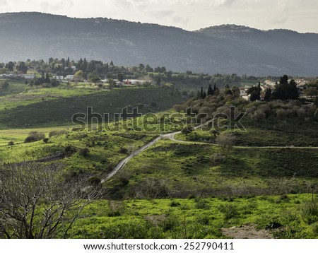 An uphill path crossing in a sunny green valley - landscape
