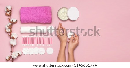 Spa concept. Cotton pads for removal makeup with woman hands, cotton branch, cotton pads, ear sticks, pink towel. Cotton Cosmetic Makeup Removers Tampons. Flat lay background Top view copy space