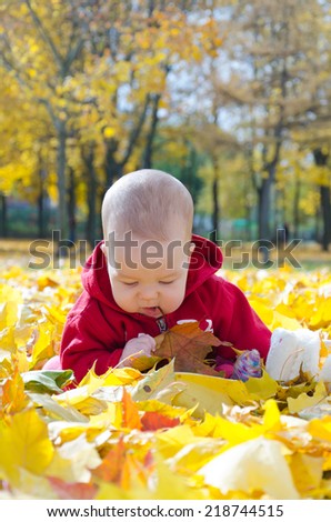Little baby in yellow autumn leaves