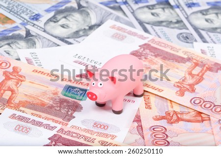 Toy pink pig standing on Russian rubles and dollars