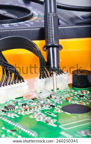 The probe of the digital multimeter on the electronic Board, shallow depth of field