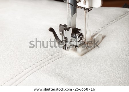 sewing machine and white leather with a seam close-up