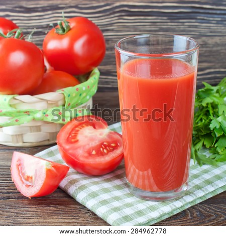 Glasses of tomato juice and fresh tomatoes on brown wooden table