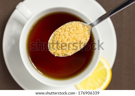 Adding brown sugar to a cup of tea