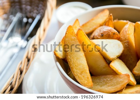 Fried potato wedges in a bowl with white garlic sauce