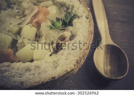Retro style photo of traditional polish cabbage soup in a loaf of bread