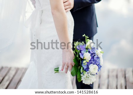 the groom and the bride with a bouquet from blue and white flowers; wedding concept
