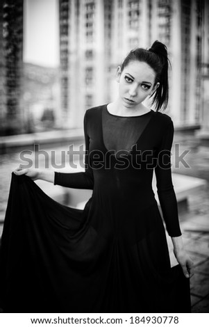 Brunette skinny woman in high fashion designer dress on roof black and white