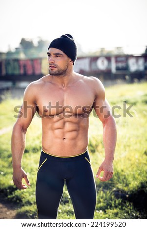 Handsome strong muscular athletic man working out outdoors in nature