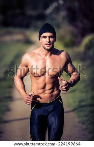 Handsome strong muscular athletic man working out and running outdoors in nature