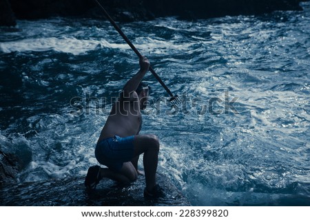 Young handsome man hunting fish the old way. Fishing with spearheads, with snorkel and flippers on. Survival training, extreme sports