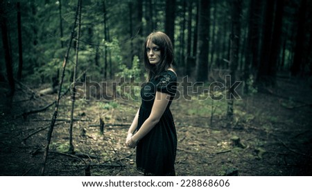 Brunette abused sad crying woman portrait in forest. Girl lost in forest. Woman lost, sad, disoriented and scared. Victim of violence and sexual abuse