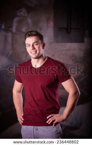 Fitness shaped muscle man posing in gym. Portrait of a athletic man after doing exercises. Smiling young man in the gym smiling. Fitness trainer / instructor
