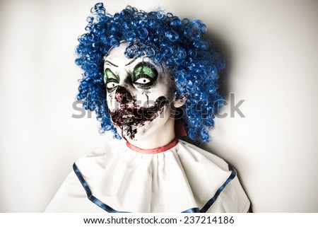 A closeup of a scarier clown with sharp pointy teeth glaring at you. Crazy ugly grunge evil clown on Halloween. Scary professional Halloween masks