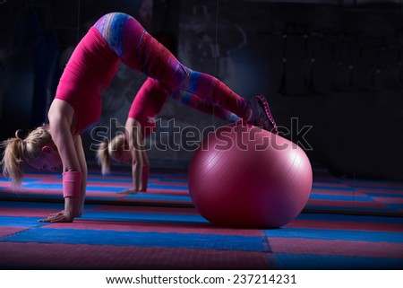 Young and athletic girl using fitness ball in a gym. Fitness ball at gym workout fitness and pilates exercise.Young woman doing some pilates exercises with a ball