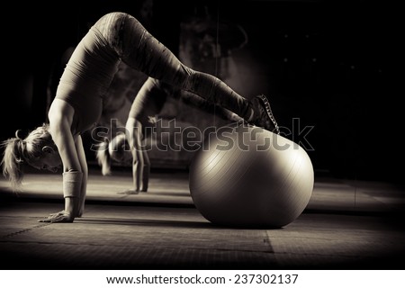 Young and athletic girl using fitness ball in a gym. Fitness ball at gym workout fitness and pilates exercise.Young woman doing some pilates exercises with a ball