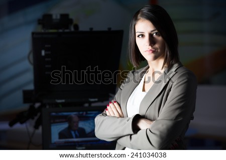 Young beautiful brunette television announcer at studio standing next to the camera.TV director at editor in studio.Recording at TV studio with television anchorwoman. TV NEWS studio with camera.