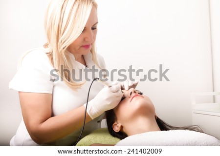 Professional cosmetician tattooist making permanent make up.Permanent make-up (tattoo).Cosmetologist applying permanent make-up on eyelids.Cosmetologist making permanent make up in beauty salon.