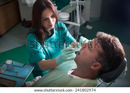 Middle aged patient in the dental clinic with the dentist doctor and nurse / assistant. Middle aged man fixing teeth in dental clinic