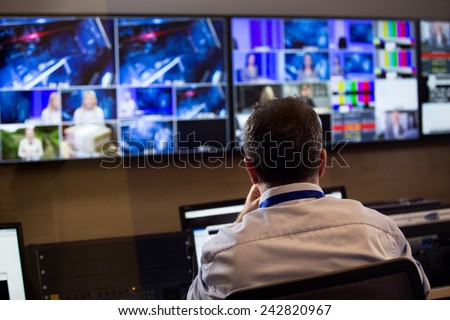TV director at editor in studio. TV director talking to vision mixer in a television broadcast gallery.Man sat at a vision mixing panel in a television studio gallery