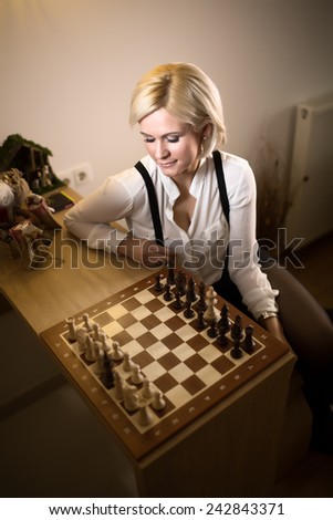 Beautiful blonde woman playing chess.Concept of rules,steps and decisions we take in life.Woman leaned,thinking about her next move.Business strategy concept.
