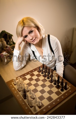 Beautiful blonde woman playing chess.Concept of rules,steps and decisions we take in life.Woman leaned,thinking about her next move.Business strategy concept.