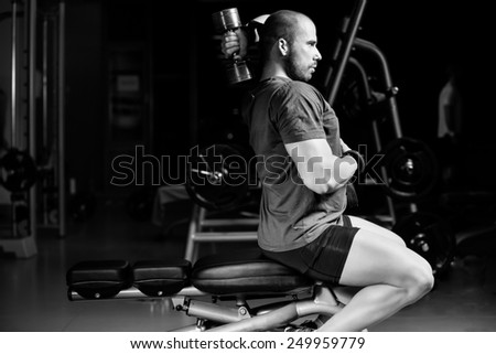 Handsome attractive muscular man training in the gym.Young muscular man doing exercises for triceps with dumbbell on gym on Scott bench