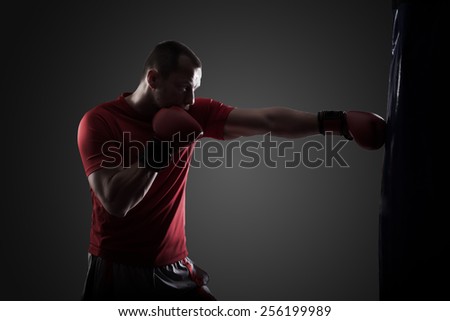 Kick boxer boxing as exercise for the big fight. Boxer hits punching bag. Young boxer trains on punching bag