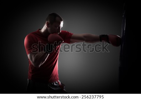 Kick boxer boxing as exercise for the big fight. Boxer hits punching bag. Young boxer trains on punching bag