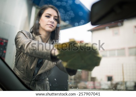Young woman, driver, dry wiping her car with microfiber cloth after washing it, cleaning auto, automobile windows. Transportation self service, care concept. Paint protection