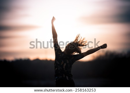 Happy girl jumping on the dawn time.Happy woman jumps to the sky in the yellow meadow at the sunset.Happy woman jumping against sunset. Freedom concept. Enjoyment.