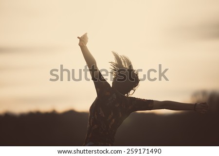 Happy girl jumping on the dawn time.Happy woman jumps to the sky in the yellow meadow at the sunset.Happy woman jumping against sunset. Freedom concept. Enjoyment.