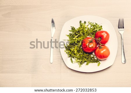 Fitness concept with healthy dieting and healthy lifestyle.Concept of diet,health and nutrition.Vibrant colorful vegetables on plate.Eating salad.Bright red tomatoes and rucola diet meal
