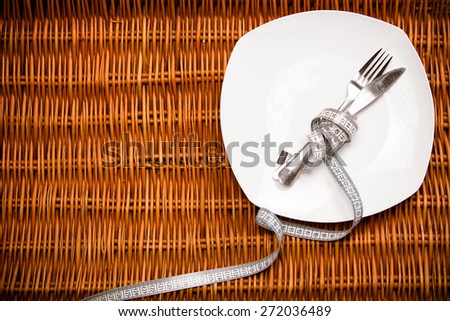 Empty plate with measure tape, knife and fork. Diet food on wooden table.Fitness concept with healthy dieting.Healthy lifestyle concept, diet and fitness