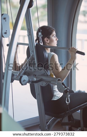 Woman weight training at gym.Exercising on pull down weight machine.Woman doing pull-ups exercising lifting dumbbells.Cardio and fat loss workout in the gym.Sport and fitness,summer body goals