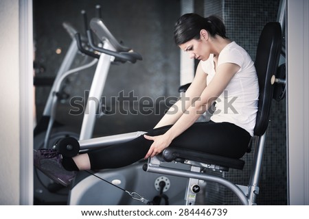 Young woman doing exercises in the gym.Gym fitness health club with young woman training legs with weights.Woman training legs in gym. Young woman making an effort and training hard for hot fit body