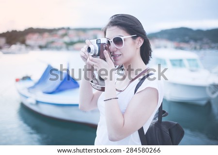 Attractive  woman  taking pictures with vintage retro camera laughing and smiling happy during summer holiday vacation travel.