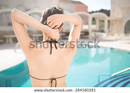 Young beautiful woman  in sexy bikini at the pool.Enjoying summer and sun.Young slim fit tanning woman having fun near poll .Vacation mood.
