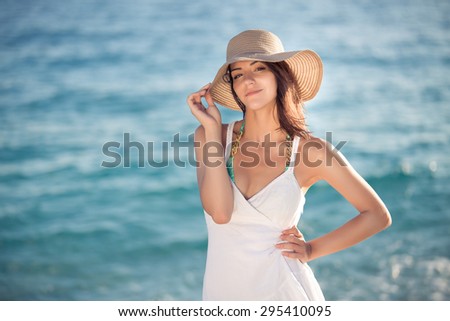 Summer beach fashion woman enjoying summer and sun,walking the beach near clear blue sea,smiling at camera.Concept of summer feeling,freedom,happiness.Fit and healthy summer body