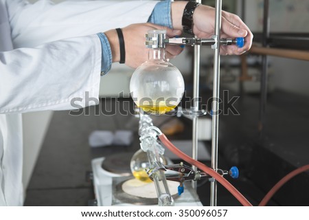 Laboratory equipment for distillation. Separating the component substances from liquid mixture with evaporation and condensation. Student/intern/technician demonstrating experiment. Making the aparature