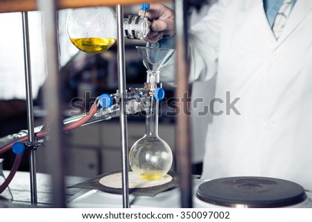 Laboratory equipment for distillation. Separating the component substances from liquid mixture with evaporation and condensation. Student/intern/technician demonstrating experiment. Making the apparatus