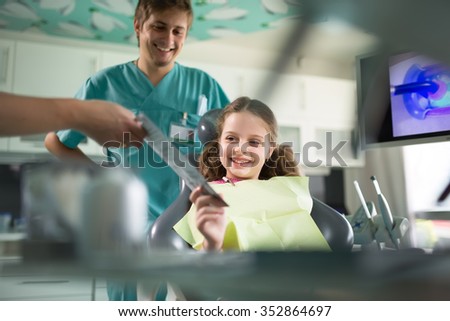 Little girl is having her teeth examined by dentist.Little girl sitting and smiling in the dentists office.Child not afraid of dentist.Dentist gives the patient a toothbrush and toothpaste.Dental care