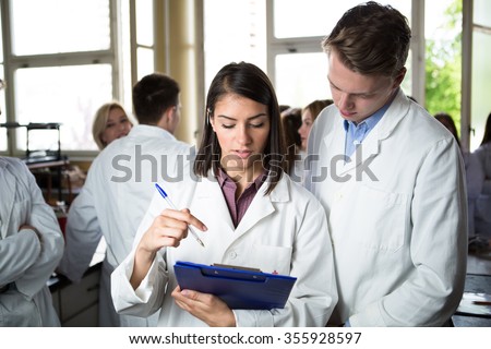 Scientific researcher holding a folder of chemical experiment research. University coworkers,Pharmacy,Medicine.Working in teams for a better result.Science project team work.