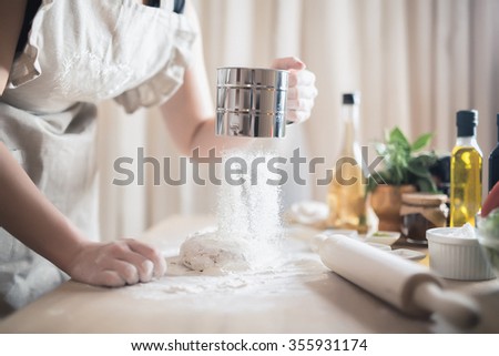 Woman preparing dough basis.Ingredients for baking.Female hands spilling powder on dough.Making dough by female hands.Cooking and baking concept