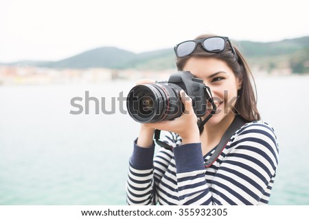 Happy woman on vacation photographing with a dslr camera on the beach and smiling.Vacation photography travel concept