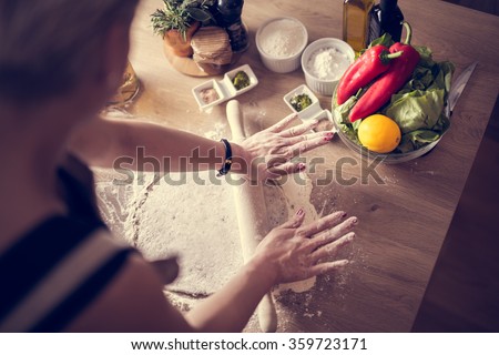 Woman cooking healthy balanced food.Carbohydrates.Whole grains.Dieting.Cooking food at home.Woman preparing dough on wooden table in the kitchen.Rolled out dough on table with rolling pin.Pizza crust